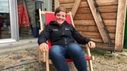 Skipperin Clara Weimer sitzt in einem Liegestuhl und lächelt in die Kamera. © NDR Foto: Antje Kasemeyer