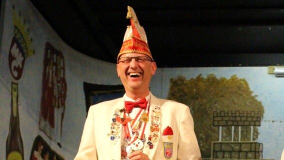 Heiko Claußen, der Präsident der Marner Karnevalsgesellschaft, steht lachend auf einer Bühne. © Heiko Claußen 