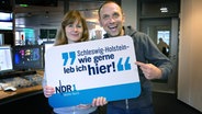 Julia Torn und Jan Bastick mit einem Schild auf dem steht: Schleswig-Holstein - wie gerne leb ich hier! © NDR Foto: Juliane Thomas