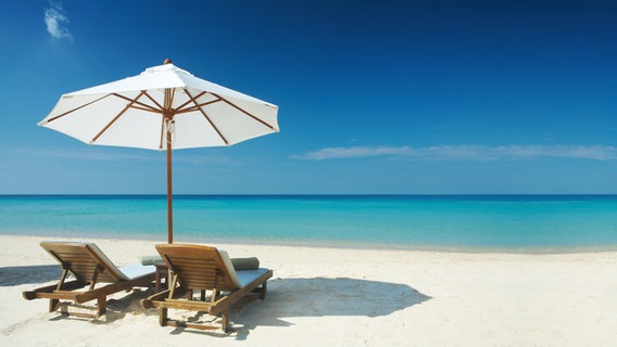 Zwei Liegen und ein Sonnenschirm am Strand. © Dmitry Ersler / fotolia Foto: Dmitry Ersler