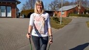 Ina Bartels steht mit Nordic Walking Sticks auf der Straße. © NDR Foto: Jörn Schaar