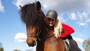 Eine blonde Frau mit einem Reiterhelm sitzt auf einem Pferd. © Tanja Niels Foto: Tanja Niels