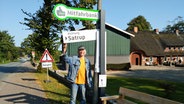 Hanno Otzen steht vor der "Mitfahrbank" in Hürup. © NDR Foto: Lukas Knauer