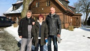 Jens Totzke, Gudrun Totzke und Loits Bürgermeister Johann Peter Christiansen stehen im Schnee vor einem ländlichen Haus. © NDR Foto: Nils Hansen