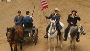 Maik Sommer (2.v.r.) reitet mit Fahne auf Pferd.  Foto: Karl May Festspiele