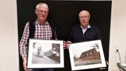 Erich Scholz und Werner Junge stehen nebeneinander und halten beide gerahmte Fotos in den Händen. © NDR Foto: Lukas Knauer