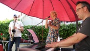 Sängerin Lene Krämer hat mit zwei anderen Musikern einen Auftritt im Freien. © NDR Foto: Astrid Wulf
