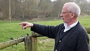 Dieter Haker aus Bäk schaut auf seine Wiese hinterm Haus, an deren Rand die Bäk langläuft © NDR Foto: Thomas Lenz