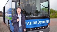 Top-Schleswig-Holsteiner Diplom-Biblilothekar Harald Gäble aus Barkelsby steht vor dem Bus der Fahrbücherei © NDR Foto: Iris Guhl-Lengeling