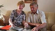 Top Schleswig-Holsteiner Heinrich Witten aus Bliestorf sitzt mit seiner Frau Hannelore auf der Couch und schaut in ein Fotoalbum © NDR Foto: Friedrich Keller