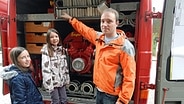 Top Schleswig-Holsteiner Henning Plaug aus Boksee zeigt zwei Kindern das Ineere eines Feuerwehrautos © NDR Foto: Ines Barber