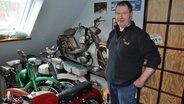 Ein Man steht in einem Zimmer voller Oldtimer-Mopeds © NDR Foto: Jörn Schaar