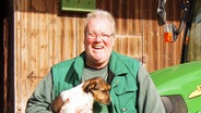 Ralph Möller hält einen Hund auf dem Arm und lacht dabei. © NDR Foto: Andrea Ring