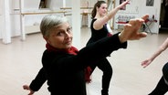 Eine ältere Frau tanzt mit einer Gruppe in einem Studio. © NDR Foto: Jörn Schaar