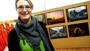 Eine Frau steht vor einer Wand mit Fotokalendern. © NDR Foto: Thorsten Philipps
