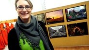 Eine Frau steht vor einer Wand mit Fotokalendern. © NDR Foto: Thorsten Philipps