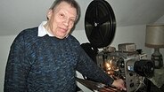 Hans Behrens aus Brande-Hörnerkirchen präsentiert stolz einen alten Kinoprojektor. © NDR Foto: Tobias Senff