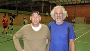 Rolf Britz und Karl Reimer (r.) stehen in einer Turnhalle und lächeln in die Kamera © NDR Foto: Frank Hajasch