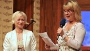 Zwei Frauen stehen bei der Preisverleihung vom "Vertell doch mal!"-Schreibwettbewerb auf der Bühne. © NDR Foto: Oke Jens