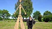 Künstlerin Eve Wiemer aus Bunsoh lehnt an einer Skulptur © NDR Foto: Peter Bartelt
