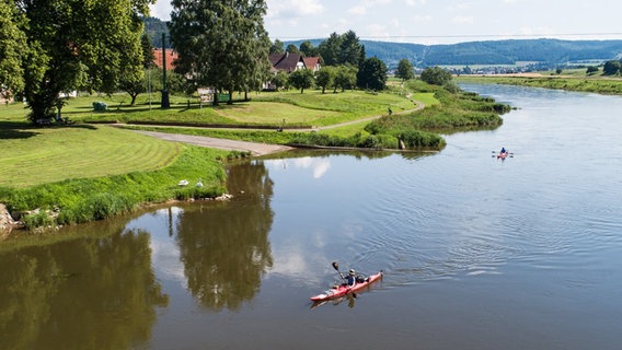 Zwei Paddler fahren die Weser Landschaft entlang.  