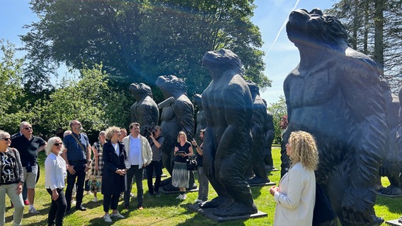 Eine Gruppe von Menschen steht vor großen Affen-Figuren im Freien. © NDR Foto: Hauke Sievers