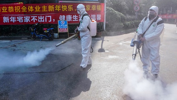 Zwei Personen in Schutzkleidung desinfiziert Straßen in Wuhan © picture alliance / Xinhua News Agency Foto: Wang Yuguo
