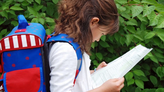 Eine Grundschülerin schaut auf ihr Zeugnis. ©  Regine Schöttl/fotolia Foto:  Regine schöttl