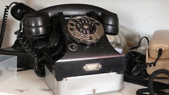 Ein altes schwarzes Telefon mit Wählscheibe steht in einem Regal  Foto: Kathrin Otto