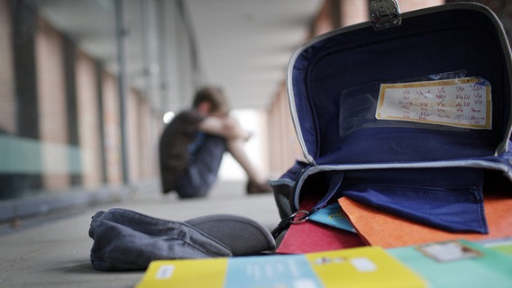 Ein Junge sitzt traurig neben seinem Schulranzen. © imago images / photothek Foto: photothek