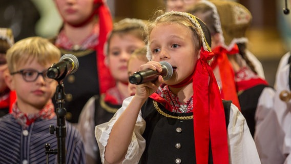 Ein Mädchen in traditioneller Tracht singt für die Lütt Finkwarder Speeldeel beim Weihnachtshafenkonzert im Hamburger Michel. © NDR Foto: Axel Herzig