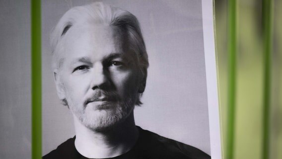 Ein Demo-Plakat vor grünem Hintergrund, das ein schwarz-weiß Porträt von Wikileaks-Gründer Julian Assange zeigt. © picture alliance / AA Foto: Rasid Necati Aslim