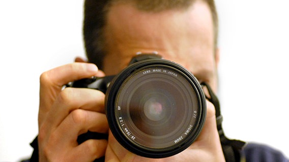 Ein Fotograf mit einer digitalen Spiegelreflexkamera © picture alliance / dpa Themendienst 