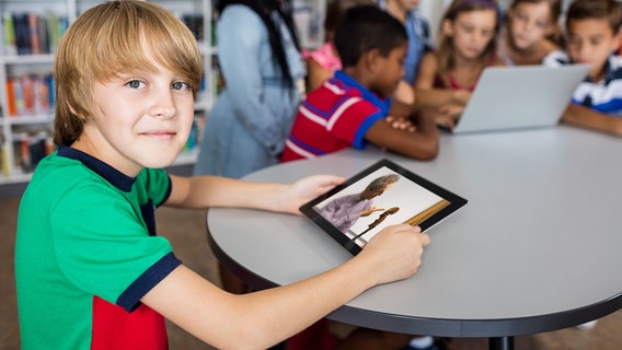 Kind mit Tablet in dem ein Musiker auf ein Cello zeigt. © Panthermedia, Foto: Wavebreakmedia ltd