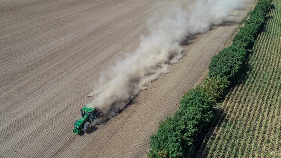 Luftaufnahme eines Traktors auf einem Feld der Staub aufwirbelt. © picture alliance Foto: Patrick Pleul