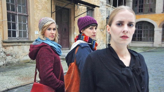 Zwei junge Frauen stehen in einem Schlosshof und schauen auf eine merkwürdig dreinblickende Frau. © NDR/ARD/Hardy Spitz Foto: Hardy Spitz