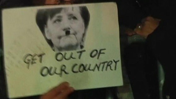 Foto von Angela Merkel mit aufgemaltem Schnauzer.  
