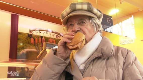 Eine Oma beisst in ein Brötchen.  