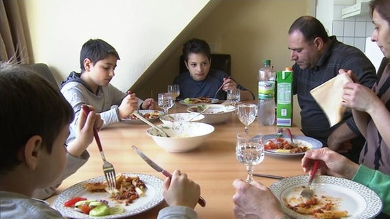 Familie Hakopjan beim Essen an einem Tisch.  