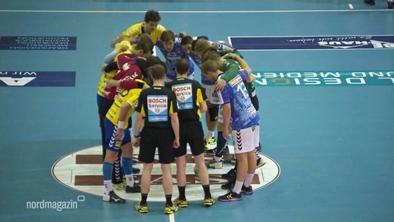 Die Spieler der Mecklenburger Stiere Schwerin und des HSV Handball bilden einen Kreis.  