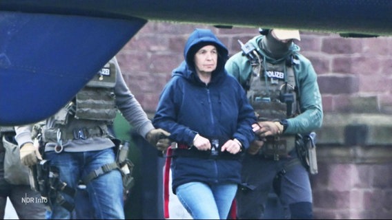 Daniela Klette wird von Polizisten zu einem Hubschrauber geführt. © Screenshot 
