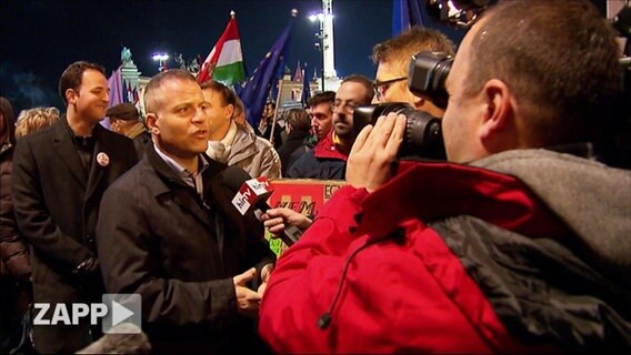 Ungarischer Politiker wird in der Öffentlichkeit interviewt.  