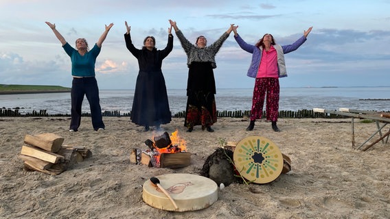 Vier Frauen stehen am Strand und strecken die Hände zum Himmel. © NDR/Anna Körber 