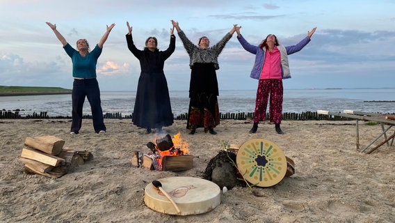 Vier Frauen stehen am Strand und strecken die Hände zum Himmel. © NDR/Anna Körber 