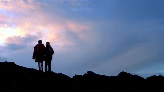 Zwei Bergsteiger beobachten den Sonnenuntergang. © NDR/photo alto 
