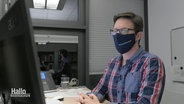 Redakteur Andreas Rabe mit Mund-Nasenschutz vor einem Rechner.  