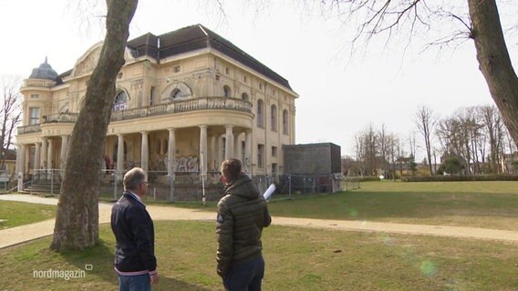 Blick auf die Villa Baltica. Davor stehen zwei Männer.  
