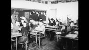 Schüler in einem Klassenzimmer heben die Hand  