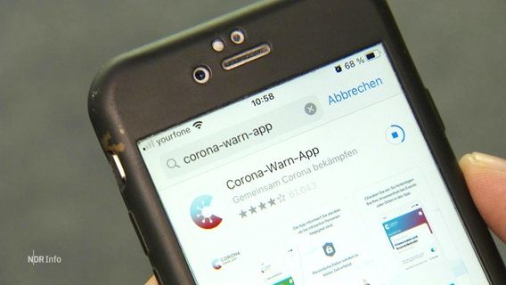 Auf einem Smartphone wird die Corona-WarnApp heruntergeladen.  