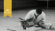 Ein Karatekämpfer zerschlägt bei einer Präsentation zehn übereinander liegende Dachziegel (1965)  